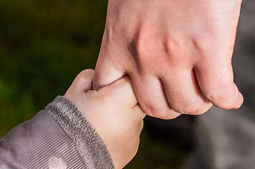 small child holding an adult's finger